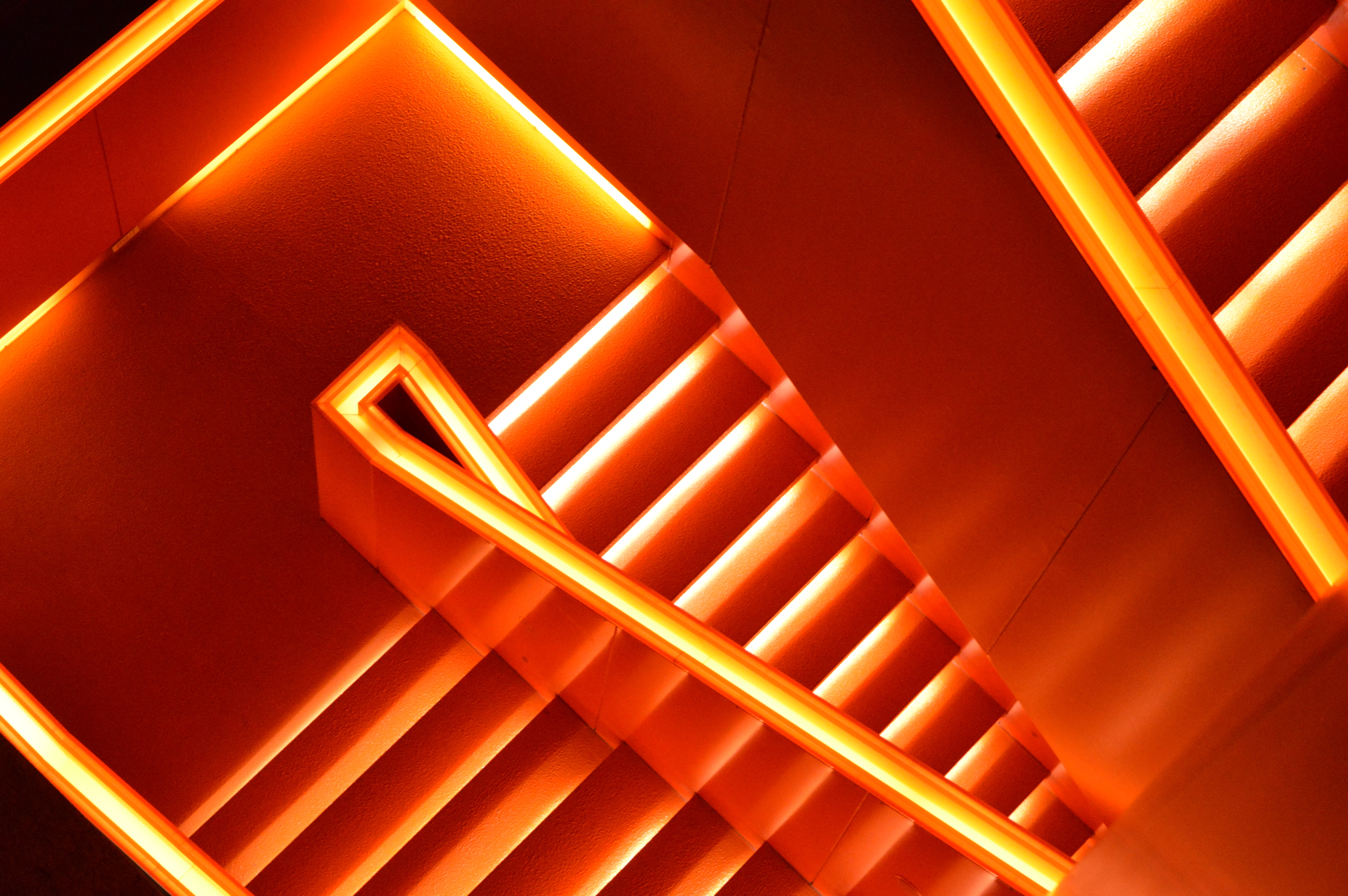 Downward view of orange neon-lit stairs